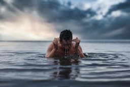 topless man in water during daytime